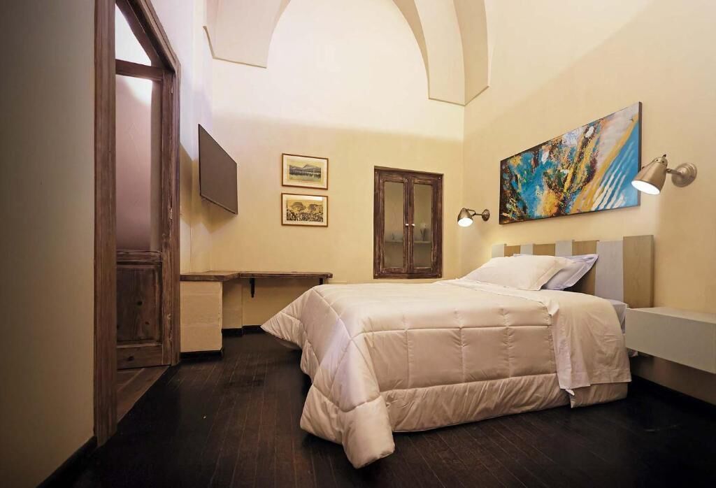 Une chambre à coucher avec un lit, un bureau, une chaise, une porte et un tableau au mur.