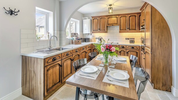 Une cuisine moderne avec des meubles en bois, un îlot central et un coin repas aménagé pour accueillir six personnes.