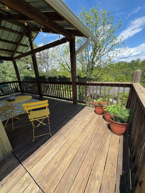 A wooden deck with a covered area, outdoor furniture, and potted plants. - Cozy Private cottage in Asheville with WiFi, AC- minutes to fun! (Asheville)