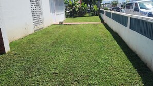 A residential area with a well-maintained lawn, white walls, and a gated entrance.