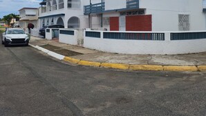 A white building with a balcony, a satellite dish, and a gated entrance.