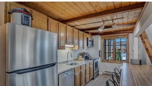 A kitchen with stainless steel appliances, wooden cabinets, and a wooden ceiling.