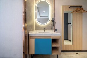 Un baño moderno con tocador, espejo y puerta de madera.