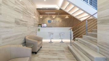 A modern reception area with a reception desk, seating, and a staircase.