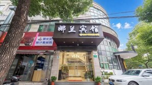 A hotel with a modern facade, a visible entrance, and a parked car outside. - Shanghai Nalan Hotel (Shanghai)