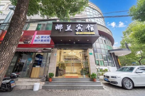 Un hotel con fachada moderna, una entrada visible y un coche estacionado afuera.