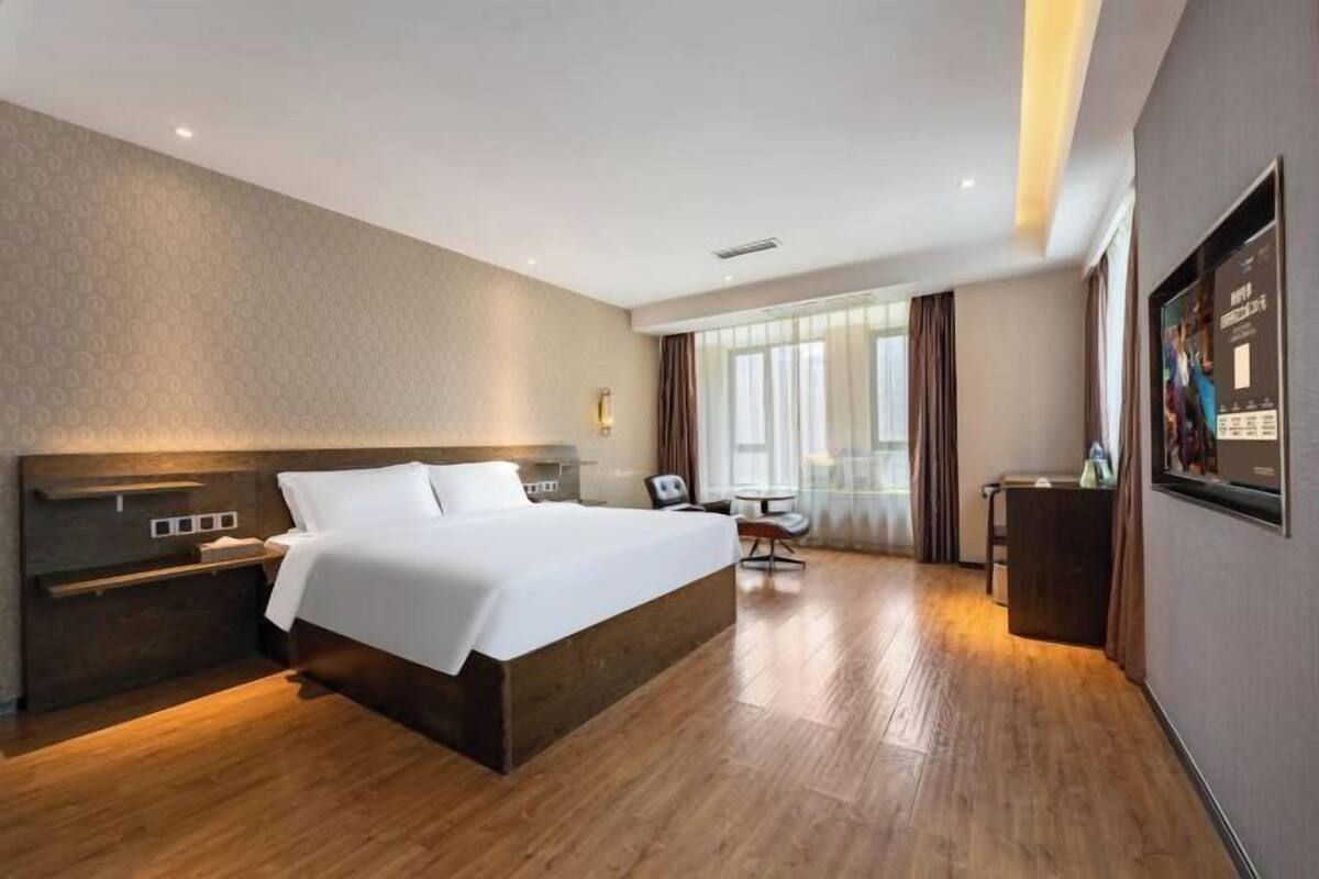 A hotel room with a large bed, bedside tables, a desk, and a chair.