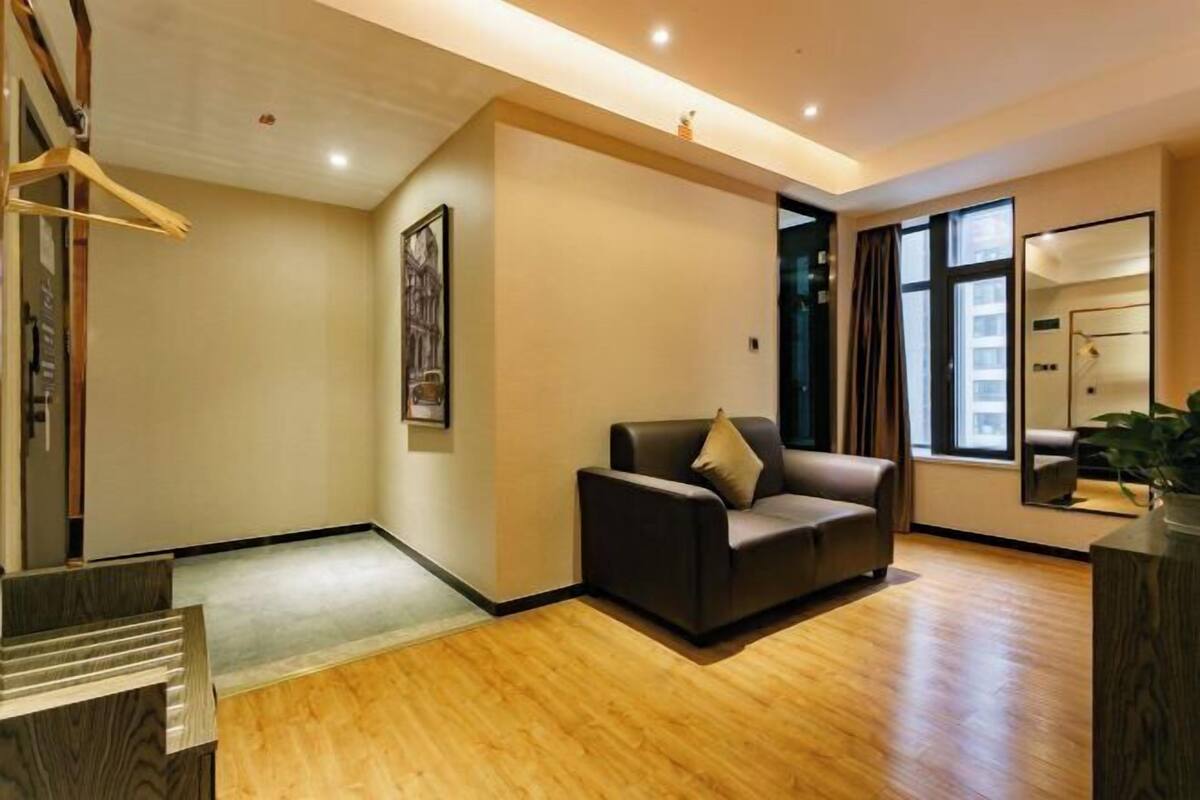 A modern living room with a sofa, wooden flooring, and a large window.