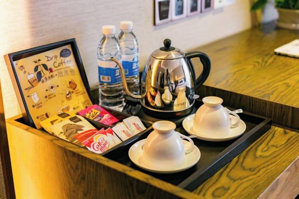 A tray with a coffee maker, two cups, and a selection of coffee pods.