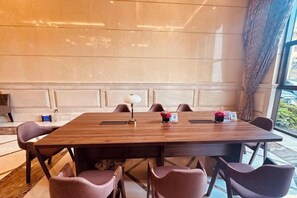 A conference room with a long table, chairs, a lamp, and a small vase with flowers. - Jinxi International Hotel (Foshan)
