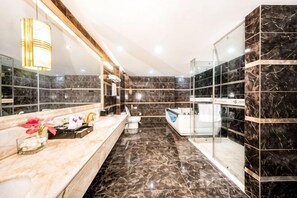 Une salle de bain moderne avec un meuble-lavabo en marbre, une cabine de douche en verre et un grand miroir.