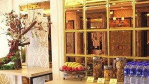 Un espace d’accueil agrémenté d’un arbre décoratif, d’un panier de fruits, de bocaux remplis de noix et de bouteilles d’eau.