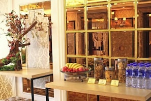 A reception area with a decorative tree, a fruit bowl, jars of nuts, and bottled water.