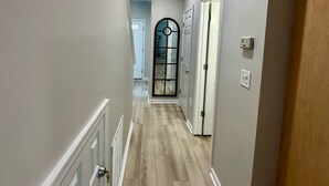 A hallway with wooden flooring, white walls, and a door with a glass panel. - 4br/3ba + pool, close to beach. Pet friendly, WiFi, Parking, Quiet neighborhood (Rehoboth Beach)