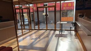 Eine Hotelhalle mit Glastür, einer Rezeption und einer Sitzecke.
