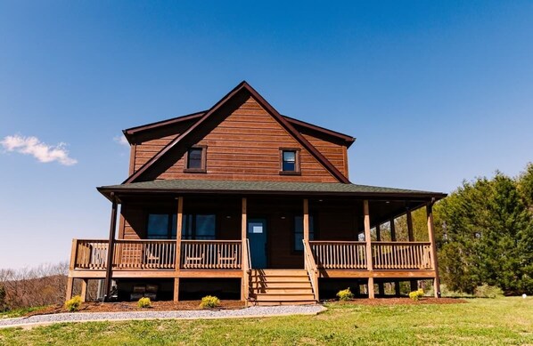 A two-story wooden house with a porch and a front door.