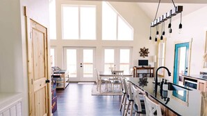 A spacious kitchen with a long island, wooden cabinets, and a large window. - Alum Ridge Retreat by Buffalo Mountain Getaway (Riner)