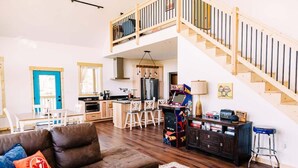 A spacious living area with a brown leather sofa, a wooden coffee table, and a kitchen in the background. - Alum Ridge Retreat by Buffalo Mountain Getaway (Riner)