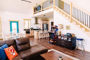 A spacious living area with a brown leather sofa, a wooden coffee table, and a kitchen in the background. - Alum Ridge Retreat by Buffalo Mountain Getaway (Riner)