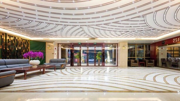 Un hall d’entrée au design moderne, avec un sol à motifs, un comptoir d’accueil et des espaces d’attente.