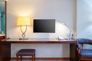 A hotel room with a desk, two chairs, a TV, a lamp, and a telephone. - Zhongyi Hotel (Guangzhou Wanda Plaza Lejia Road Metro Station Branch) (Guangzhou)
