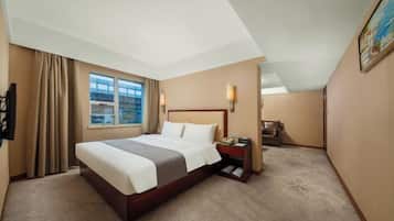 A hotel room with a large bed, a bedside table with a lamp, a window with curtains, and a painting on the wall.
