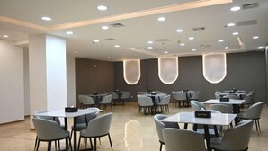 Un espace de restauration moderne, doté de tables et de chaises, d’un éclairage encastré et d’un design épuré et minimaliste.