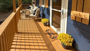 Eine Holzterrasse mit Fußmatte, Sitzgelegenheit und Kübelpflanzen.