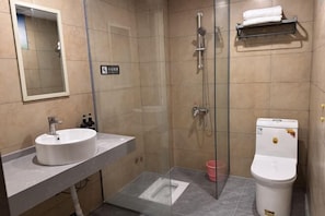 Une salle de bain moderne avec une douche à parois de verre, un lavabo blanc et des toilettes.
