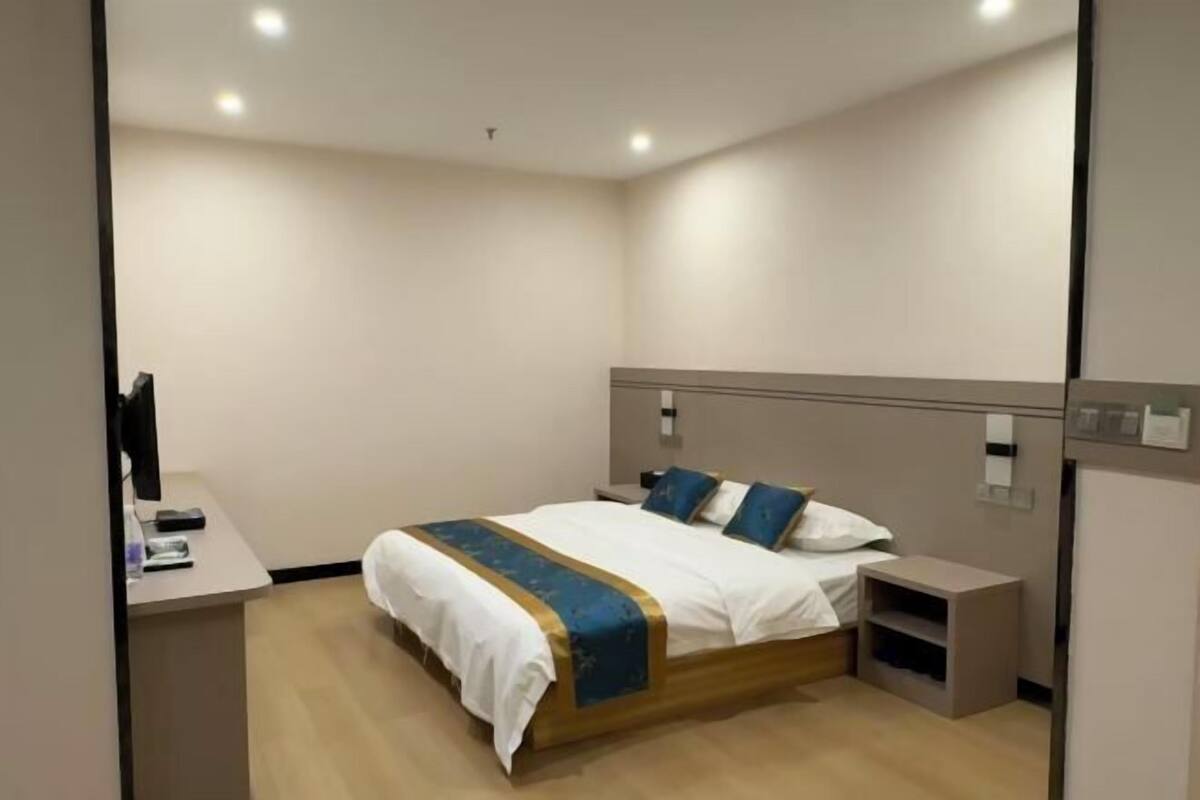 Una habitación de hotel moderna con cama, mesita de noche y escritorio con computadora.