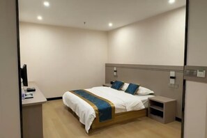 A modern hotel room with a bed, bedside table, and a desk with a computer. - Hengxian Huashi Baijie Hotel (Hengzhou)