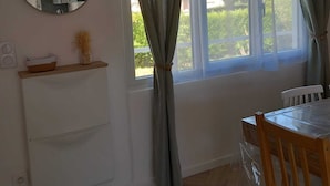 A room with a dining table, chairs, a mirror, and a window with curtains.