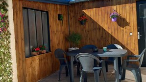 A patio with a wooden fence, a table with chairs, and potted plants.