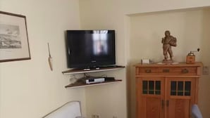 A living room with a sofa, a television, a cabinet, and a statue. - Vacation apartment no. 1, town center, Randersacker (Randersacker)