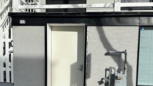 A building with a white door, a staircase, and a utility box on the side. - Beach Block Cozy studio with WiFi and FREE PARKING!! (Atlantic City)