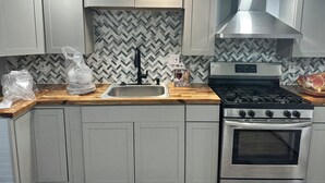 A modern kitchen with white cabinets, a stainless steel stove, and a herringbone-patterned backsplash. - Beach Block Cozy studio with WiFi and FREE PARKING!! (Atlantic City)