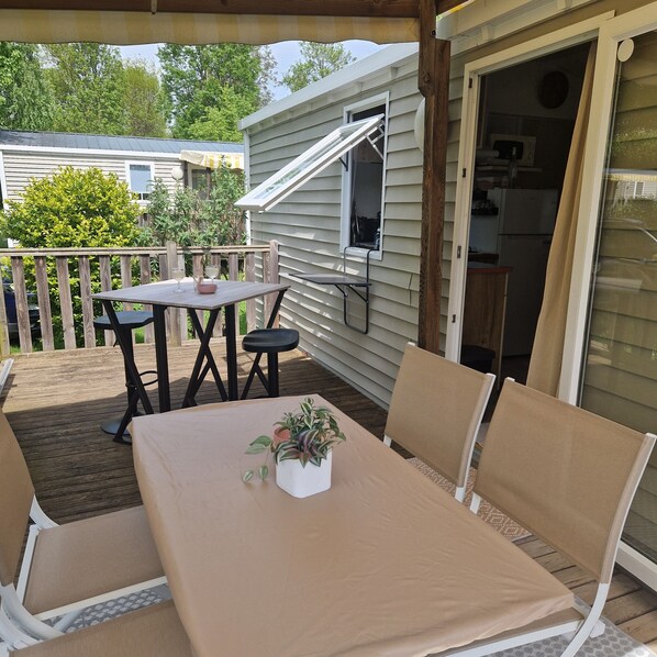 A covered patio with a table and chairs, a potted plant, and a sliding door to a kitchen area.