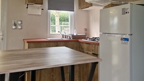 A modern kitchen with wooden cabinets, a built-in microwave, and a stainless steel refrigerator. - Mobile home number 480 in camping 4☆ (Châteauneuf-de-Galaure)