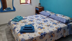 Une chambre à coucher avec un lit, un miroir, une fenêtre et un luminaire au plafond.