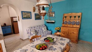 Un coin repas avec une table dressée pour deux personnes, un luminaire suspendu et un mur bleu.