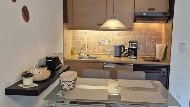 A modern kitchen with a dining area, featuring a coffee machine, a kettle, and a sink. - Vacation apartment "Amina" in Hahnenklee (Goslar)