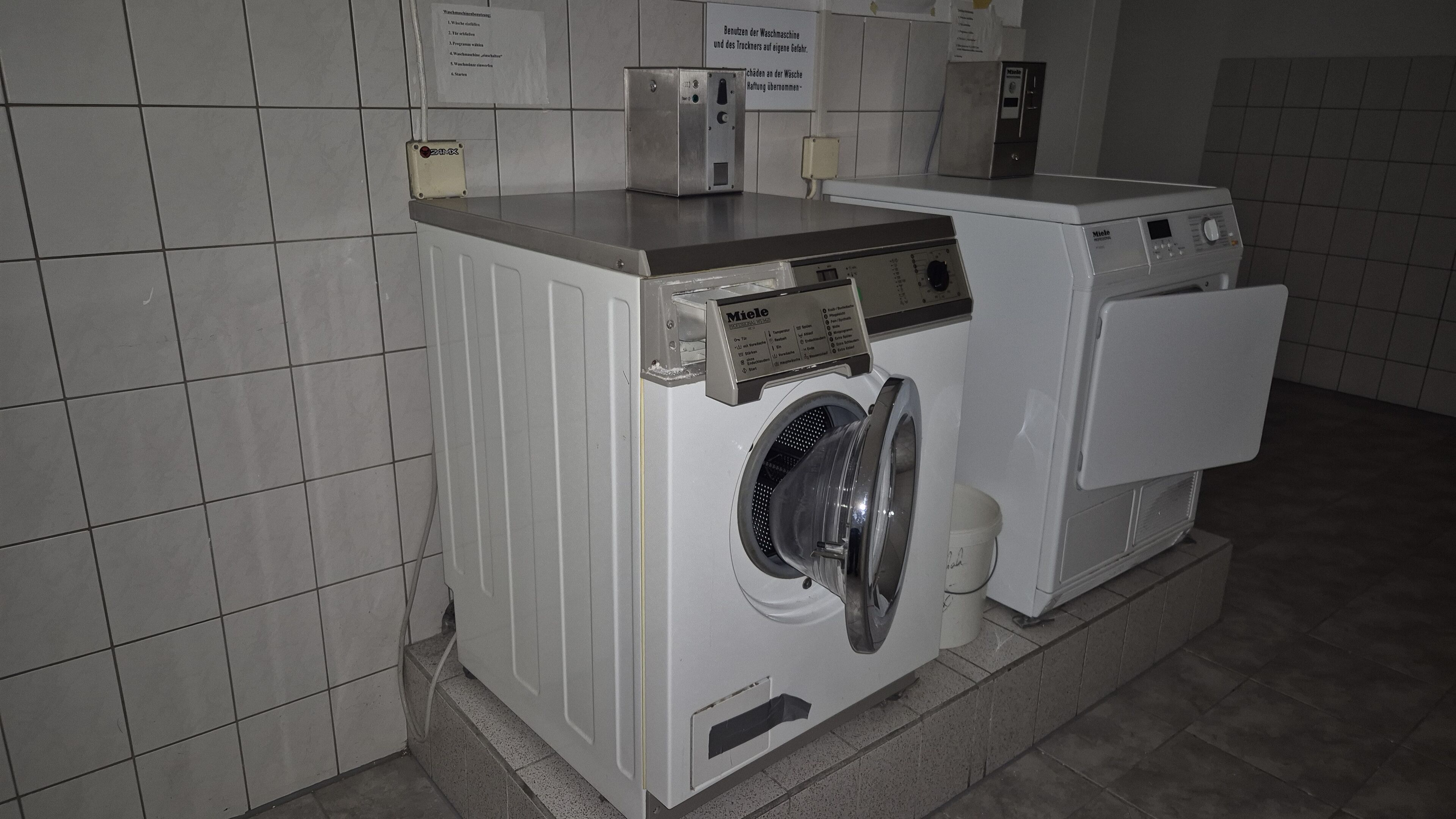 Une buanderie équipée de deux machines à laver à chargement frontal, d’un panneau de commande et d’un panneau indiquant les instructions.