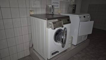 Une buanderie équipée de deux machines à laver à chargement frontal, d’un panneau de commande et d’un panneau indiquant les instructions.