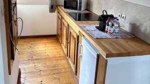 A small kitchen with wooden cabinets, a white refrigerator, a microwave, and a wooden countertop. - Duplex apartment with Alsatian decor (Beblenheim)