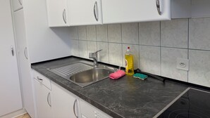Ett modernt kök med vita skåp, en diskho i rostfritt stål och en svart bänkskiva.