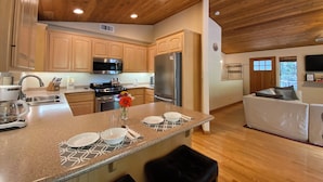 A modern kitchen with wooden cabinets, stainless steel appliances, and a central island with seating. - 15% Off September Special - Hot Tub - Dogs Welcome (Pioneer)