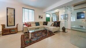 Una sala de estar moderna con un sofá seccional, una mesa de centro de vidrio y una alfombra colorida.