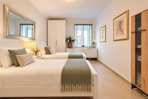 Un dormitorio con dos camas, un armario, una ventana con persianas y un cuadro en la pared.