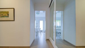 Un pasillo con un cuadro enmarcado a la izquierda, que lleva a una habitación con una mesa y sillas.