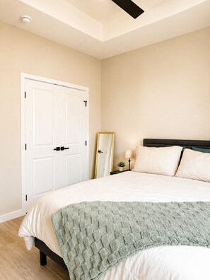 A bedroom with a bed, a nightstand, a mirror, and a door.